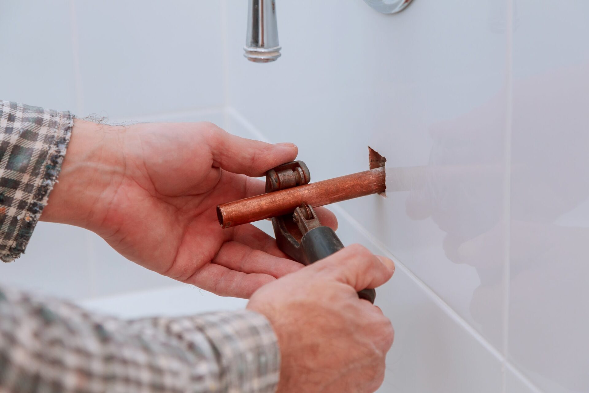 Plumber cutting copper pipe during a burst pipe repair