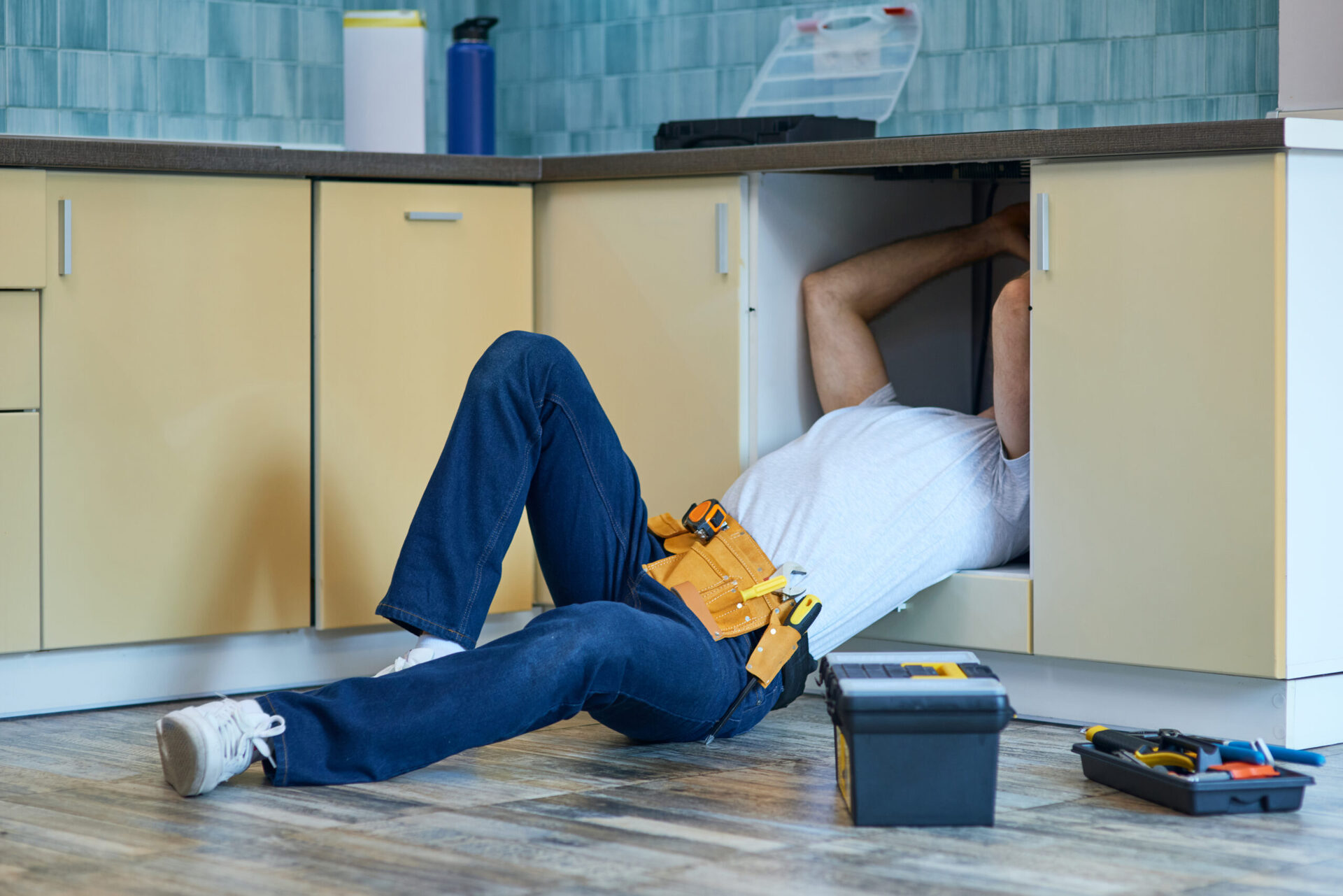 Plumber working under a sink on an emergency repair
