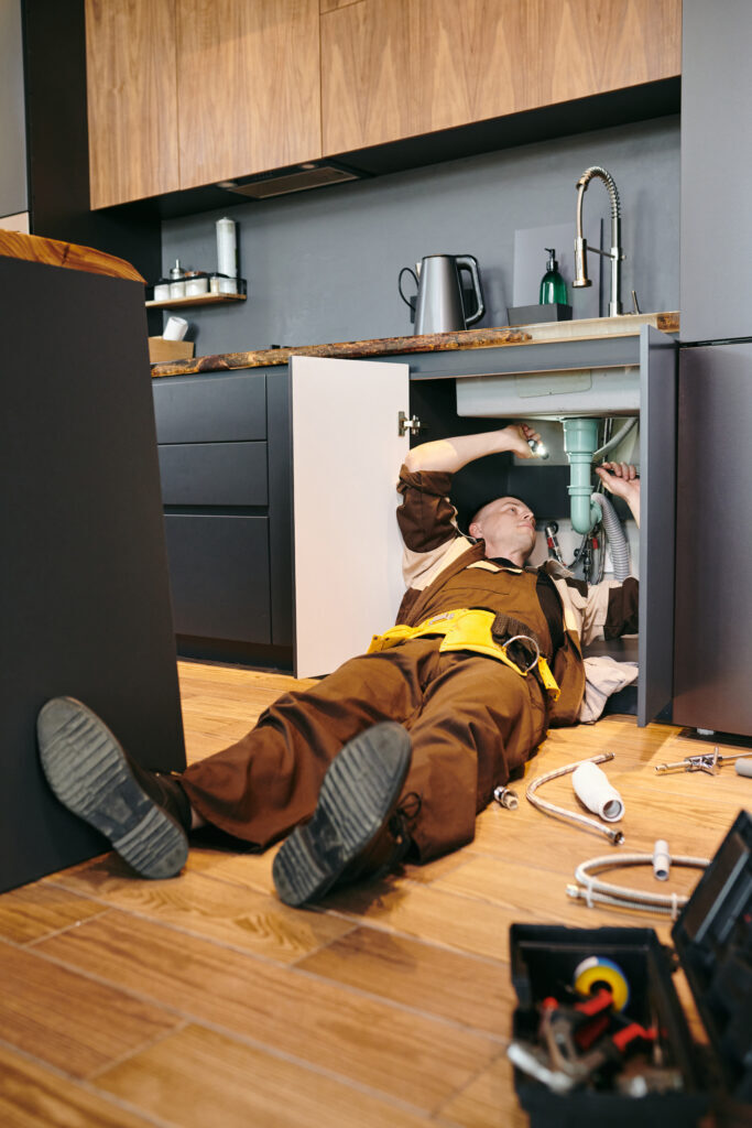 Plumber repairing a kitchen sink at home