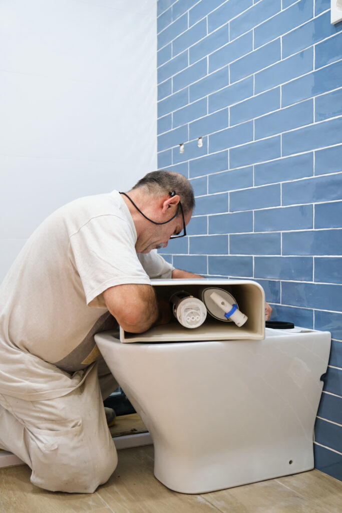 Plumber replacing a toilet in a renovated bathroom